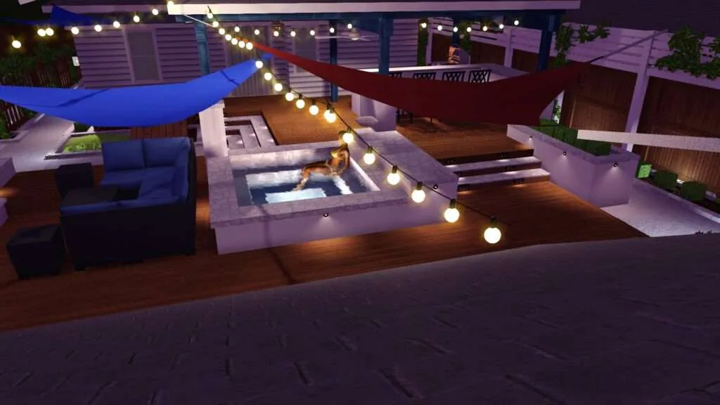 Elevated nighttime view of a modern rooftop patio with lounge seating, glowing string lights, fire pit, shade structures, and wooden decking