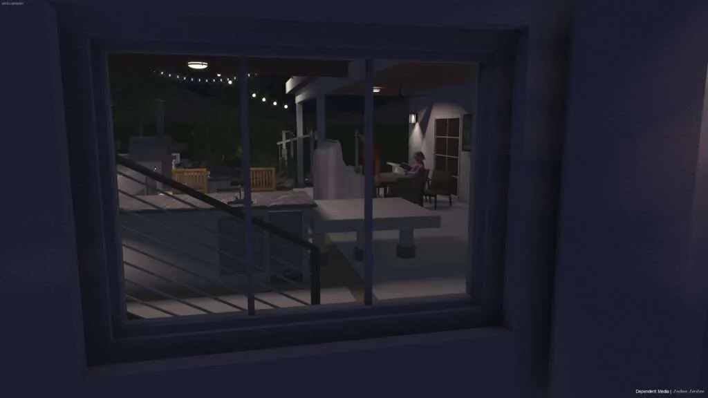 View through glass sliding door of illuminated covered patio at night with wooden chairs, string lights, and person seated inside